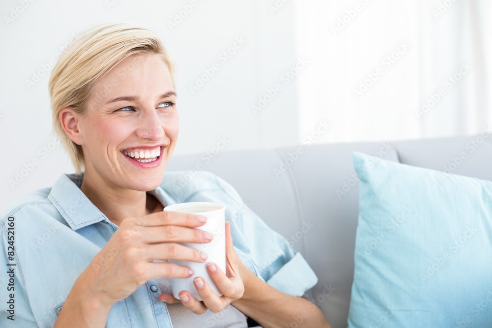Pretty blonde woman relaxing on the couch and holding a mug Pretty blonde woman relaxing on the couch and holding a mug
