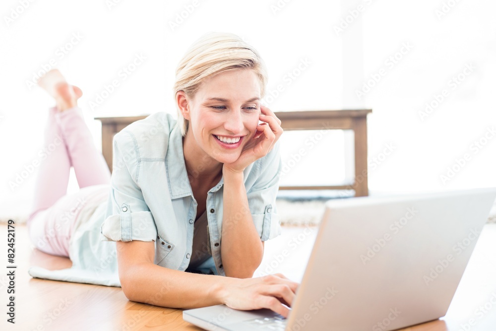 Pretty blonde woman lying on the floor and using her laptop Pretty blonde woman lying on the floor and using her laptop