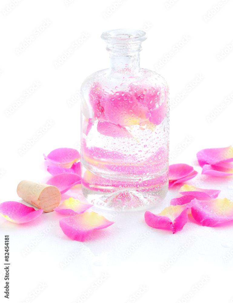 Bottle of essential oil and petal pink rose isolated on white