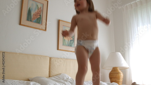 little girl jumping on bed