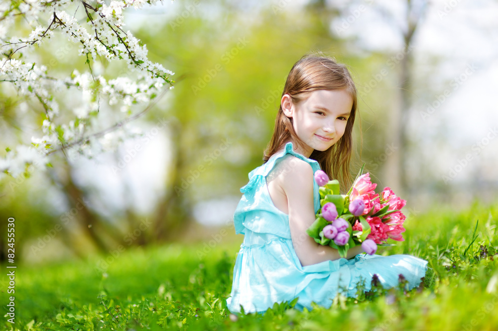 Adorable little girl in blooming cherry garden