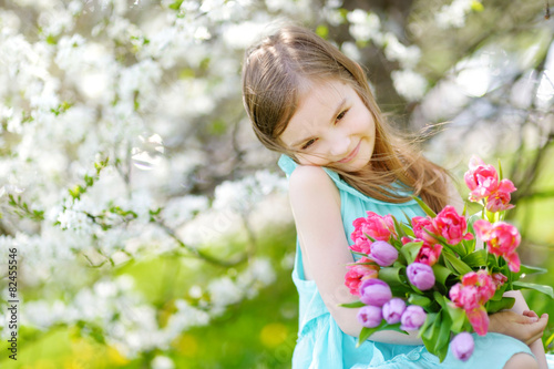 Adorable little girl in blooming cherry garden