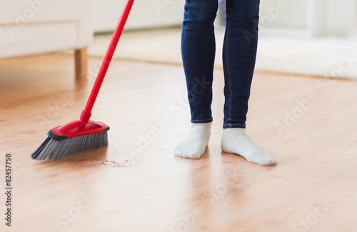 close up of woman legs with broom sweeping floor photo