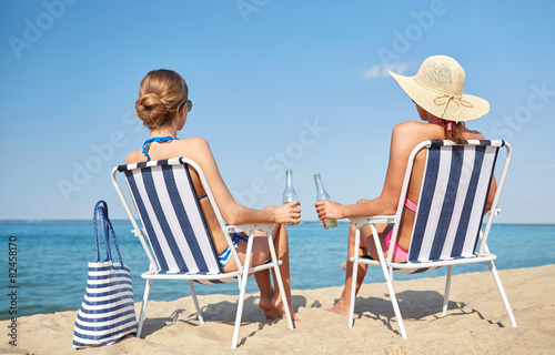 happy women sunbathing in lounges on beach