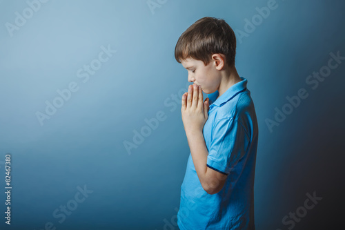boy teenager European appearance in a blue shirt brown praying c