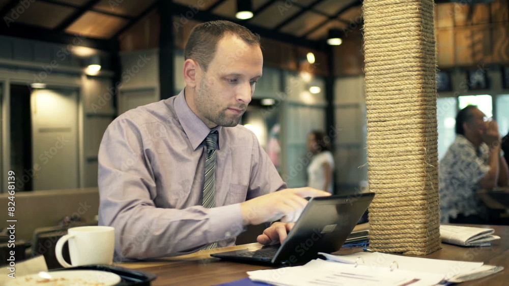 Young businessman working on laptop sitting in cafe 

