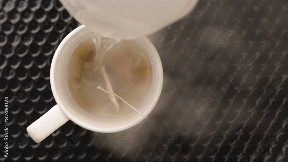 Hot water pouring in tea mug with teabag and steam rising Stock Video Adobe Stock