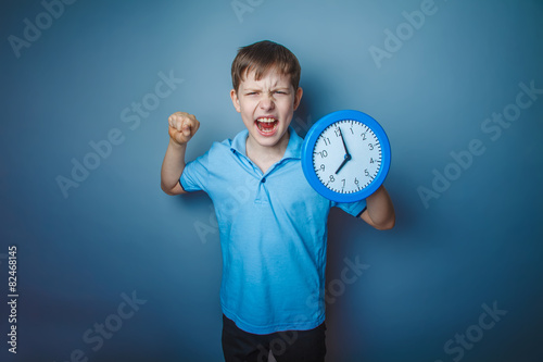 teenager boy brown European appearance holds a clock showing thu