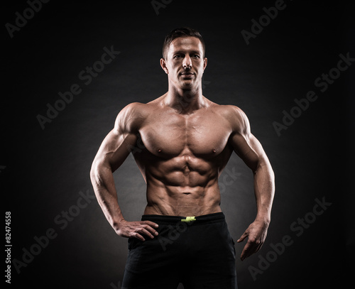 Muscular man in studio on dark background © bondarchik