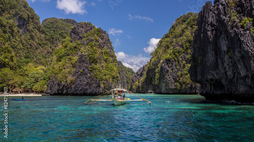 Palawan island blue turquoise Lagoon with a boat and green mountains in Philippines