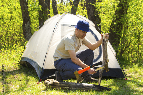 Man chopping wood to tent © phadventure