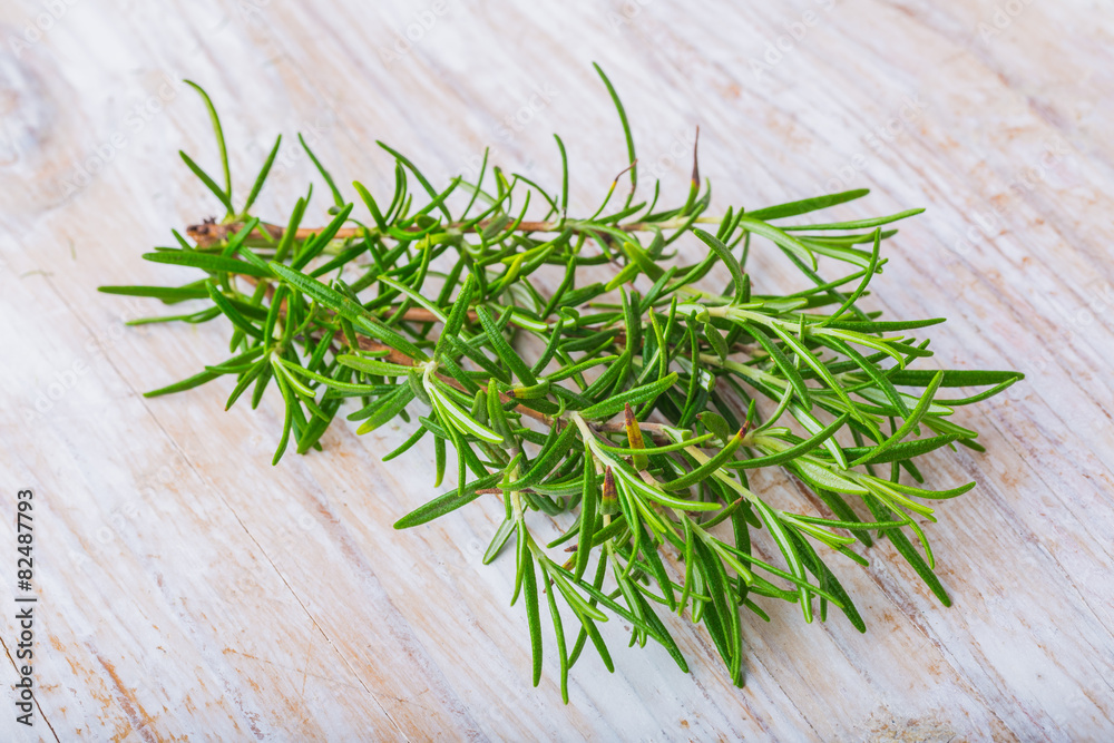 Branch of fresh rosemary on a white wooden Branch of fresh rosemary on a white wooden