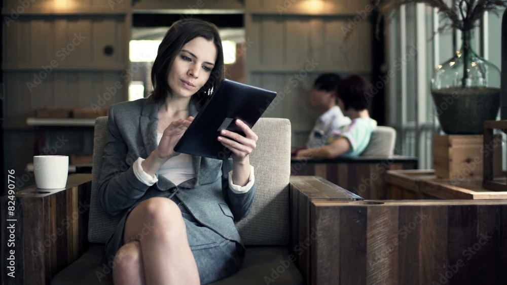 Businesswoman reading on tablet computer and drinking Businesswoman reading on tablet computer and drinking