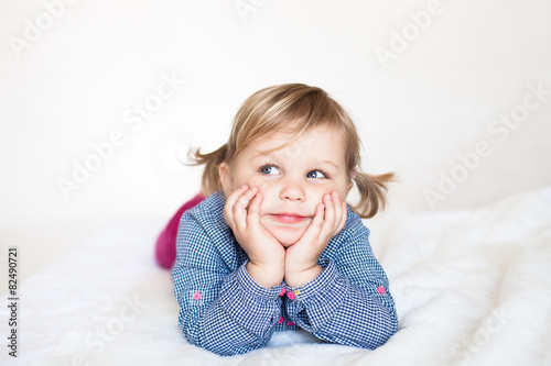 Cute smiling dreamy baby girl  lying on the white blanket