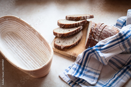 Sliced bread on a woody cutting board on desk with bascet and na