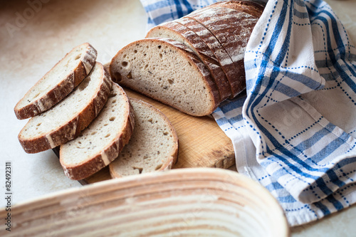 Sliced bread on a woody cutting board on desk with bascet and na