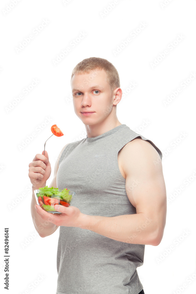 Young happy muscular man eating a salad over white background. Young happy muscular man eating a salad over white background.