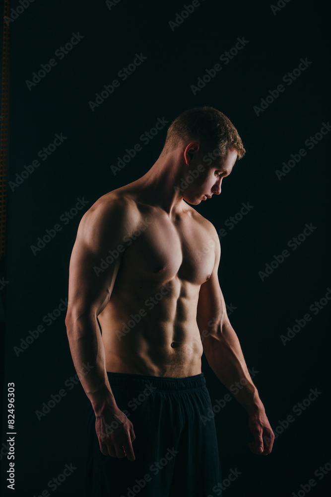 Fototapeta premium muscular young man showing his biceps isolated on black
