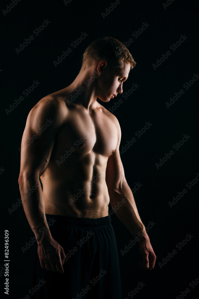 muscular young man showing his biceps isolated on black muscular young man showing his biceps isolated on black