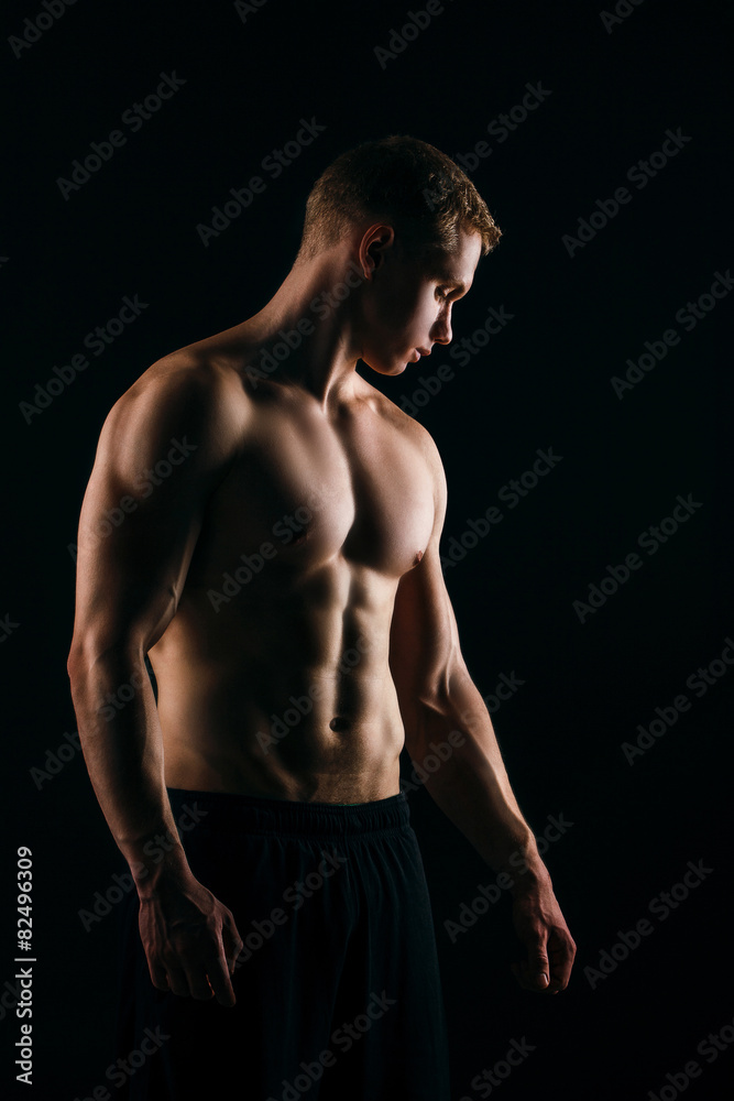 muscular young man showing his biceps isolated on black