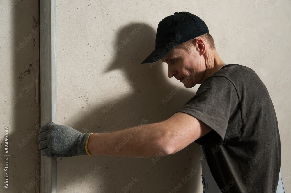 Woker fixes a guide to align the walls with stucco Woker fixes a guide to align the walls with stucco