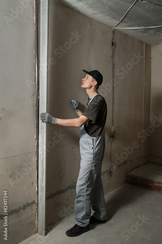 Woker fixes a guide to align the walls with stucco © yunava1