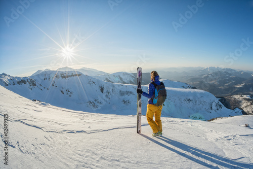 skier looking at the sunset from the top of the mountain
