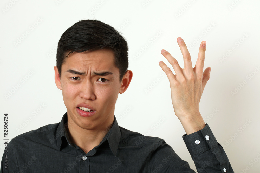 Displeased young Asian man gesturing with his hand Displeased young Asian man gesturing with his hand
