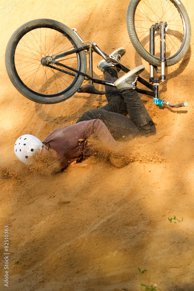 Fototapeta premium biker is falling from his mountain bike to the sand