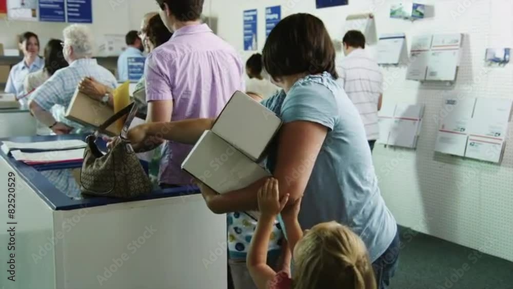 MS TU People waiting in line at post office, two daughters (4-11) pulling on mother's arm holding cardboard boxes / Orem, Utah, USA