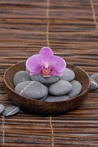 gorgeous orchid with gray stones in wooden bowl on mat 