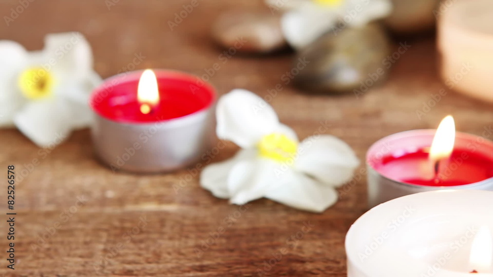 Spa still life containing towel, rocks, massage oil, candles and flowers on wood Spa still life containing towel, rocks, massage oil, candles and flowers on wood
