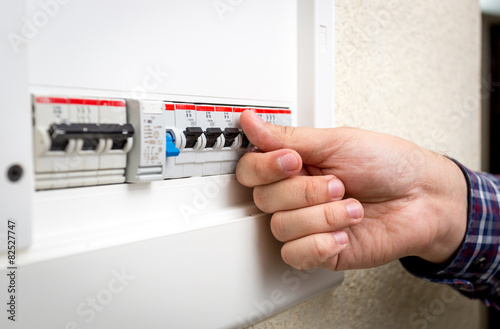 Closeup of man switching on fuseboard photo