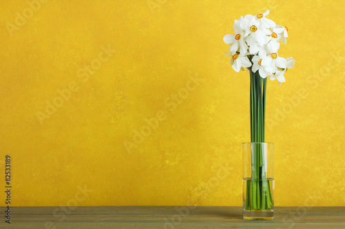 Fototapeta Naklejka Na Ścianę i Meble -  Daffodils in a glass vase on a wooden background