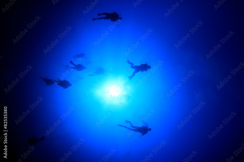 Fototapeta premium Scuba diving underwater: divers silhouette and sun