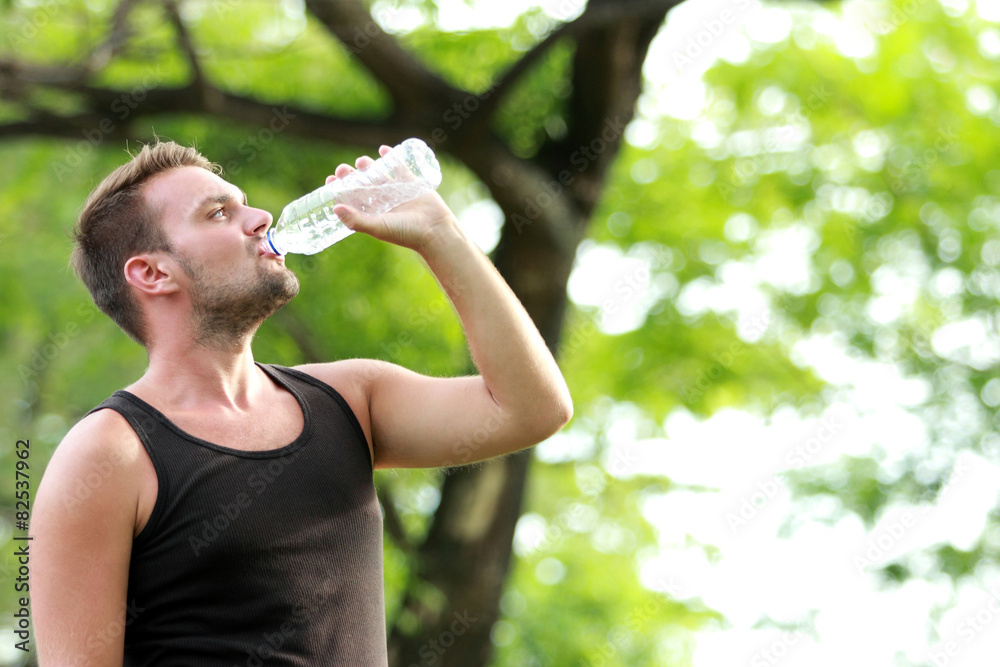male runner drinking mineral water at the break after running male runner drinking mineral water at the break after running
