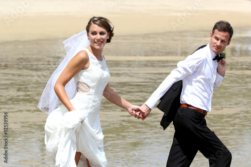 bride and groom hand to hand walking at the beach