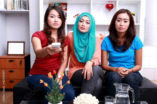 three young women with flat face expressions when watching telev photo