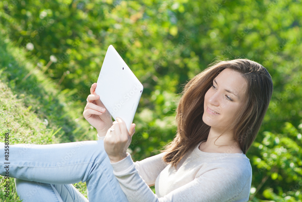 Young woman using digital tablet outdoors in park Young woman using digital tablet outdoors in park