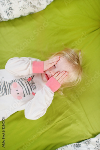 Little toddler girl in bed on sunny morning