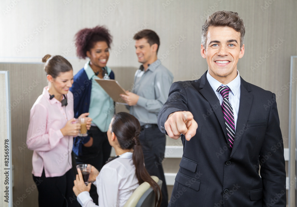 Smiling Manager Pointing While Employees Working In Background Smiling Manager Pointing While Employees Working In Background