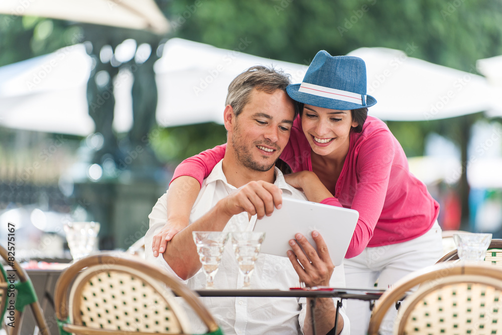 nice couple sitting on cafe terrace using a digital tablet