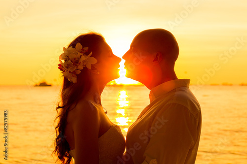 bride and groom having fun on a tropical beach with the sunset  photo