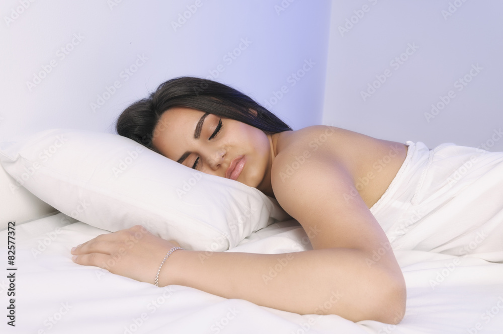 Beautiful woman lying on a bed with white sheets Beautiful woman lying on a bed with white sheets