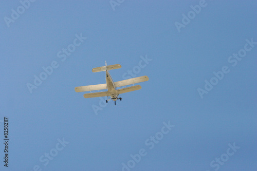 Biplane flying in the blue sky. 