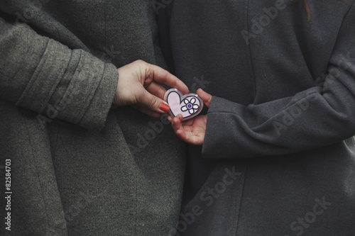 Two girls holding a heart in its hands