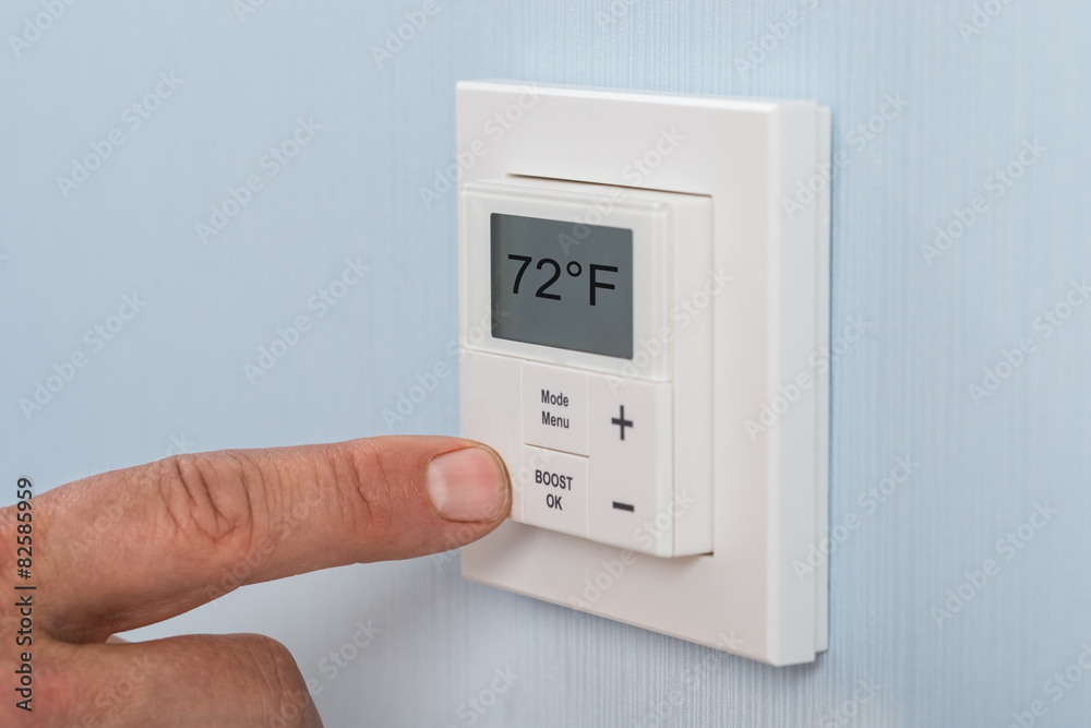 Person Adjusting Temperature Of Thermostat Person Adjusting Temperature Of Thermostat