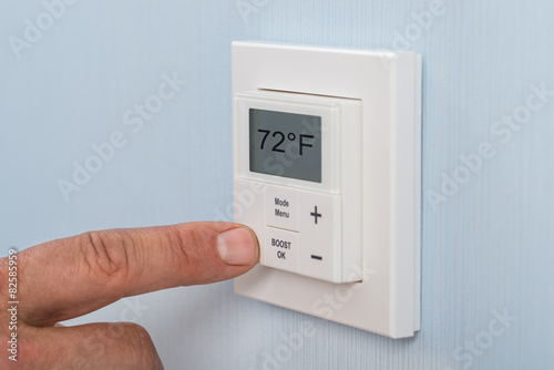 Person Adjusting Temperature Of Thermostat