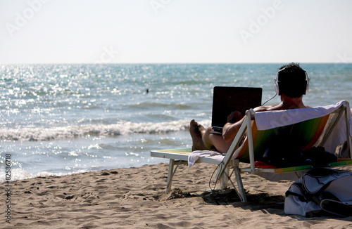 Remote working scene featuring a tropical beach and a man connected through headset and laptop