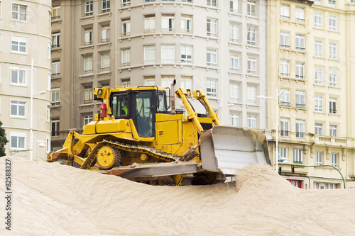yellows excavators on the city beach working sand moving